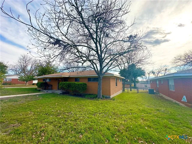 a view of a house with a yard and tree