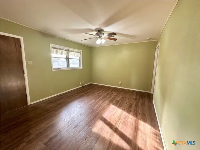 an empty room with wooden floor closet and windows