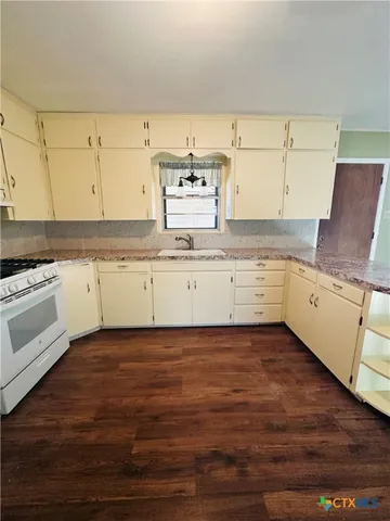 a kitchen with granite countertop a sink cabinets and stainless steel appliances
