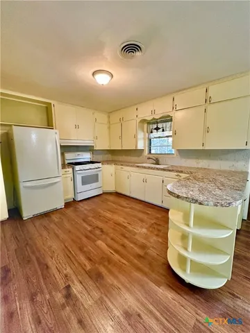 a kitchen with wooden floors and white appliances
