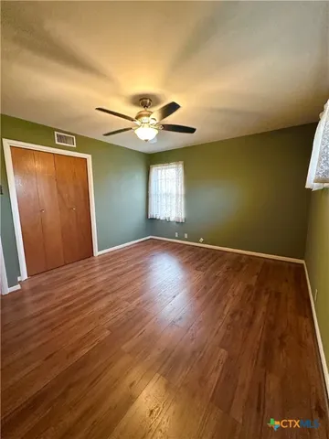 a view of a room with wooden floor and a ceiling fan