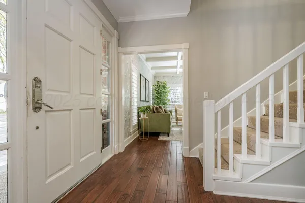 a hallway with wooden floor windows and a livingroom