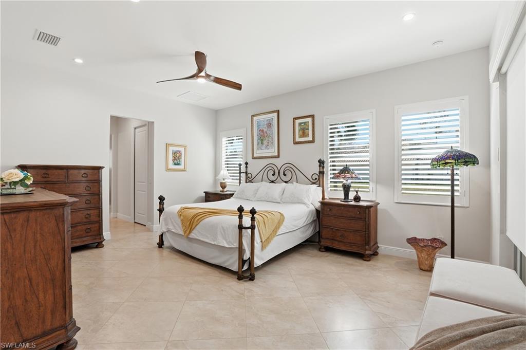 3707 5th Avenue Southwest Naples, FL 34117 - Photo 15 of 45 Oversized primary bedroom with space for sitting area, 3 windows dressed with wood plantation shutters for plenty of natural light and electric shades on impact sliders leading to the lanai