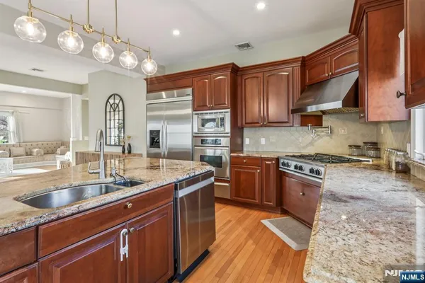 a kitchen with stainless steel appliances granite countertop a sink a stove and a wooden floors