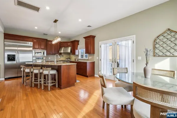a kitchen with stainless steel appliances a dining table chairs and wooden floor