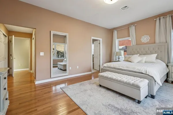 a spacious bedroom with a bed and wooden floor