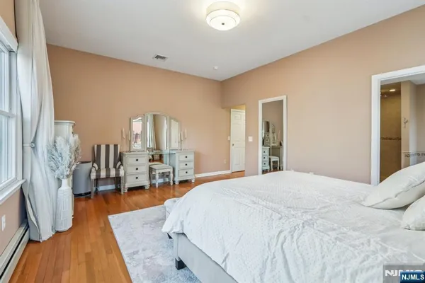 a spacious bedroom with a bed and wooden floor