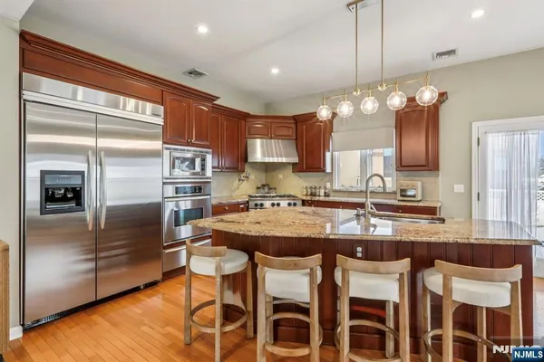 a kitchen with cabinets a counter space stainless steel appliances and a chandelier
