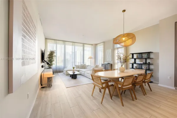 a view of a dining room and livingroom with furniture wooden floor a rug a painting and a chandelier
