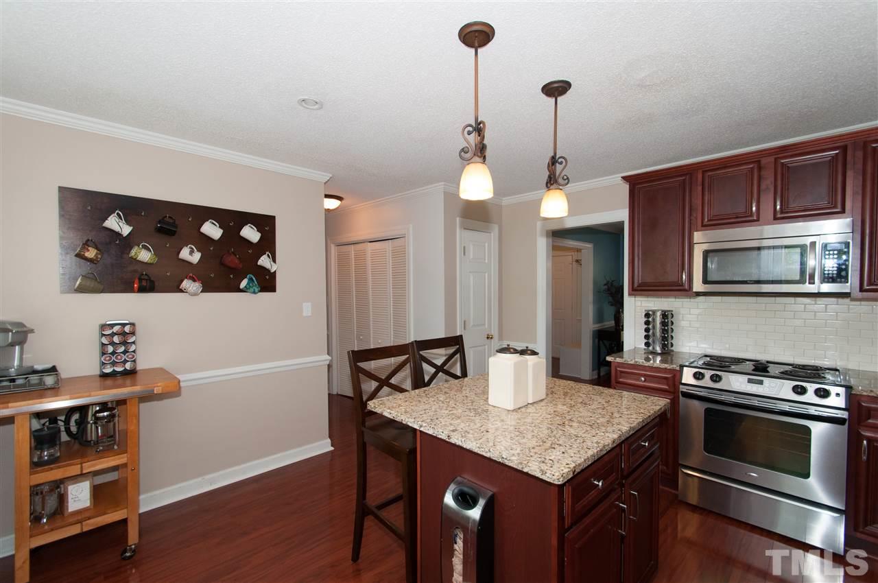 7304 Chicora Court Raleigh, NC 27615 - Photo 4 of 25 a kitchen with a stove a refrigerator and a dining table with wooden floor