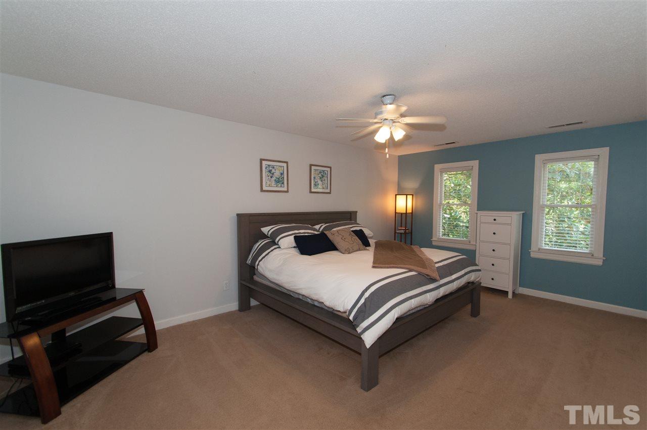 7304 Chicora Court Raleigh, NC 27615 - Photo 9 of 25 a spacious bedroom with a bed and a chandelier