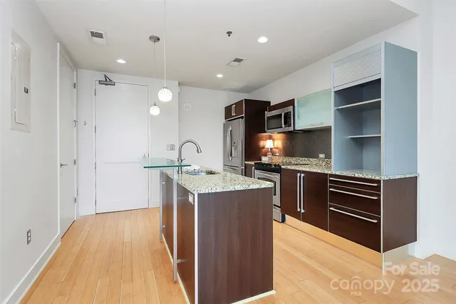 a kitchen with kitchen island granite countertop a stove and a sink