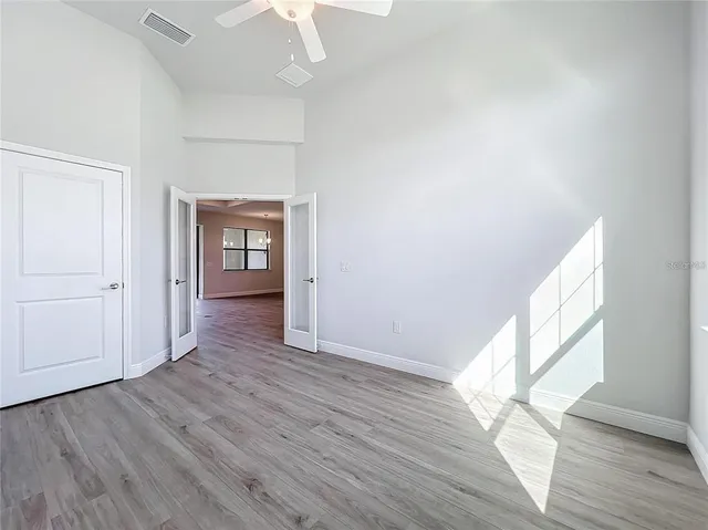 a view of empty room with wooden floor and fan