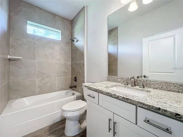 a bathroom with a granite countertop sink a toilet and bathtub