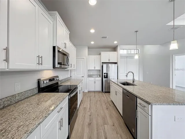 a large kitchen with stainless steel appliances granite countertop a lot of counter space and wooden floor
