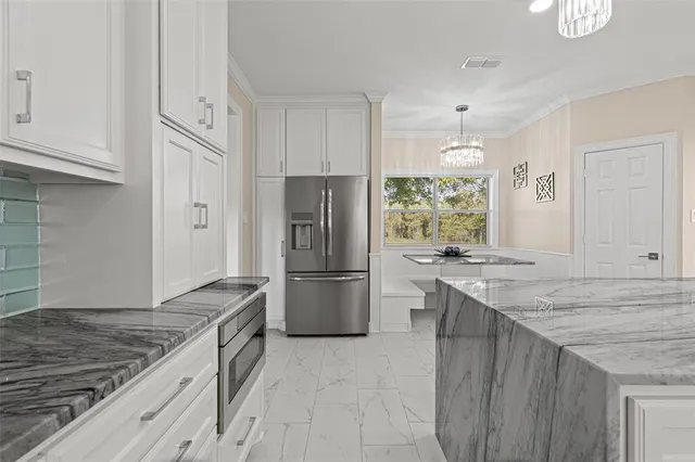 a large kitchen with stainless steel appliances kitchen island granite countertop a refrigerator and a sink