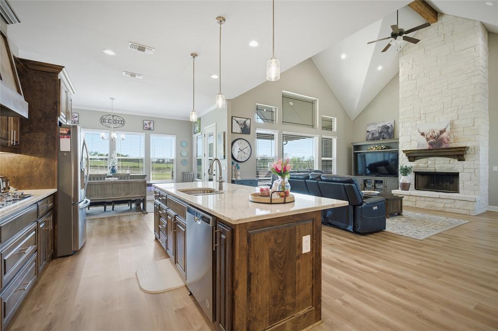 1065 Old Highway Howe, TX 75459 - Photo 18 of 39 Kitchen with light stone countertops, a stone fireplace, dark wood finish cabinets, and light wood-style floors