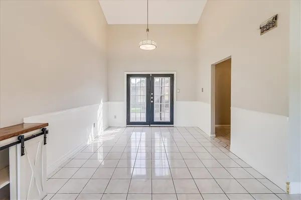 a view of an empty room with window and chandelier fan