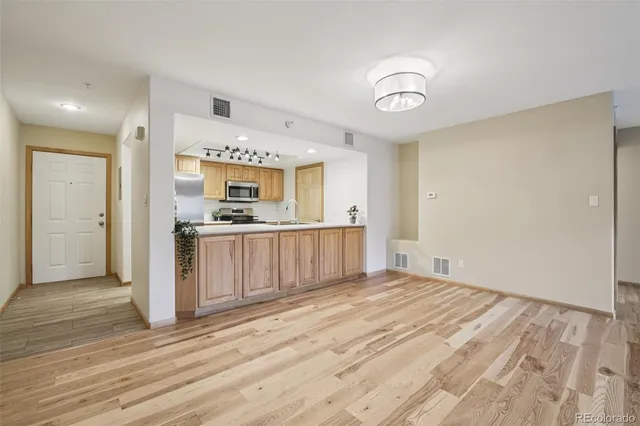 a view of a kitchen from the hallway with a sink and wooden floor