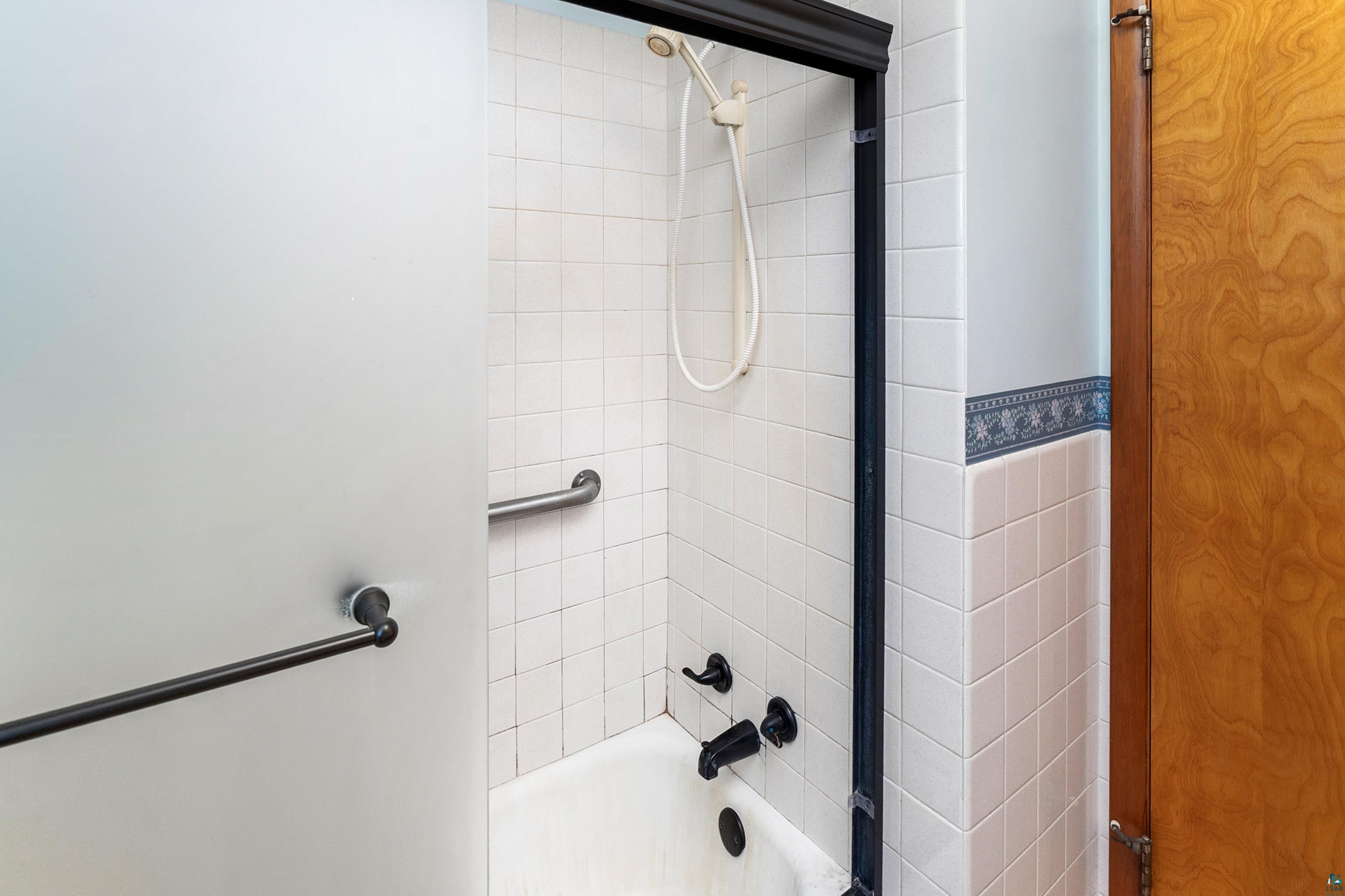 4808 Midway Road Duluth, MN 55811 - Photo 29 of 57 Bathtub with white tile surround and black-framed frosted glass shower door