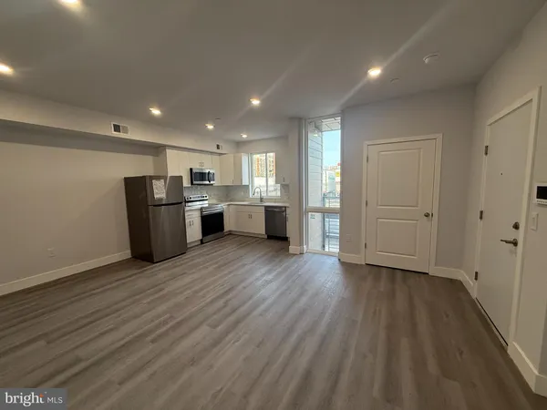 a view of a kitchen with refrigerator and wooden floor
