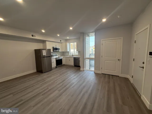 a view of a kitchen with refrigerator and wooden floor