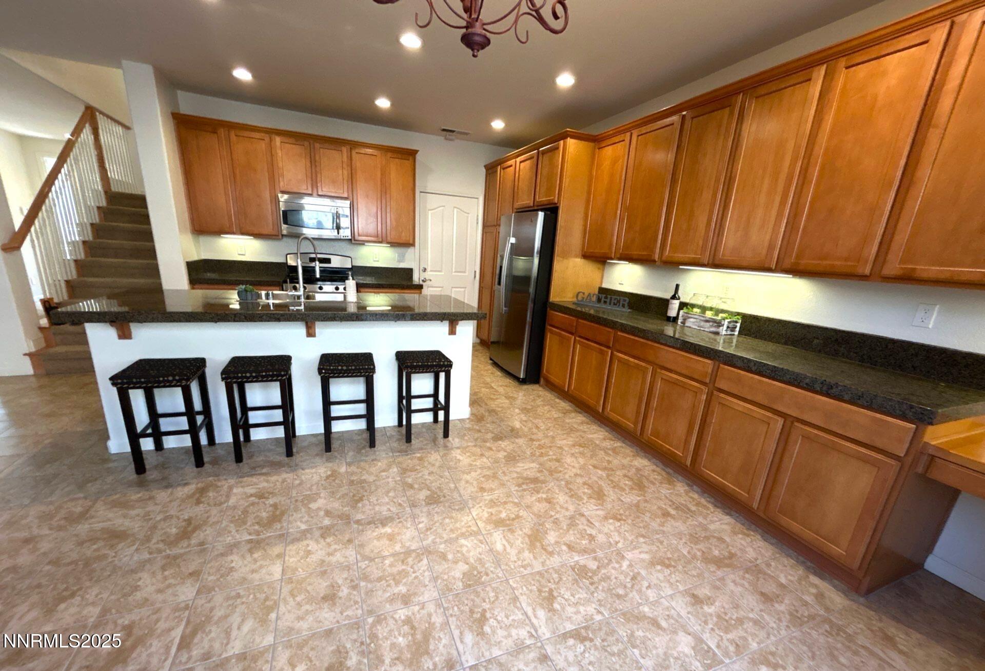 7150 Provence Circle Reno, NV 89523 - Photo 7 of 22 a kitchen with kitchen island granite countertop wooden cabinets stainless steel appliances a sink and a large window