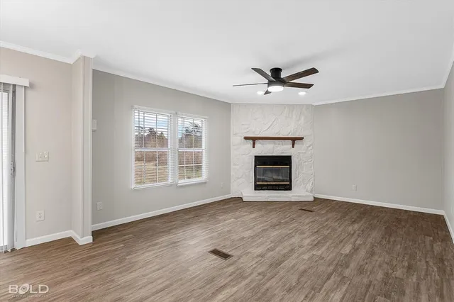 an empty room with wooden floor a ceiling fan and windows
