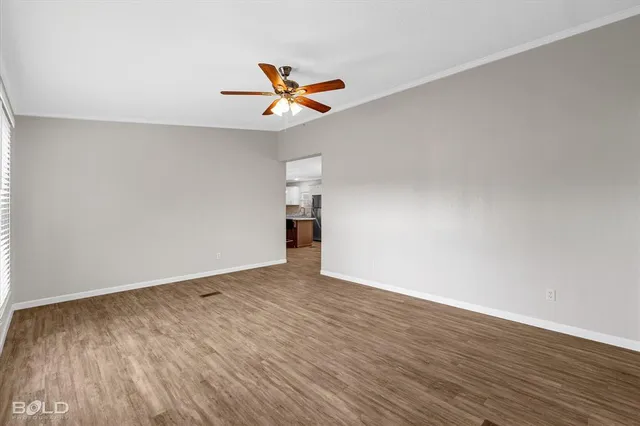 an empty room with a window and a chandelier fan