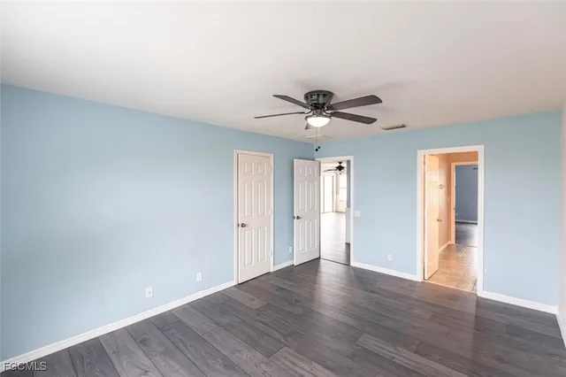 a view of an empty room with wooden floor and a ceiling fan