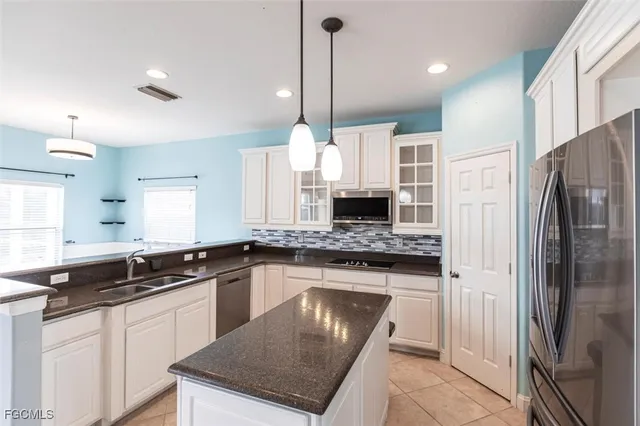 a kitchen with stainless steel appliances granite countertop a sink a stove a refrigerator and island with wooden floor