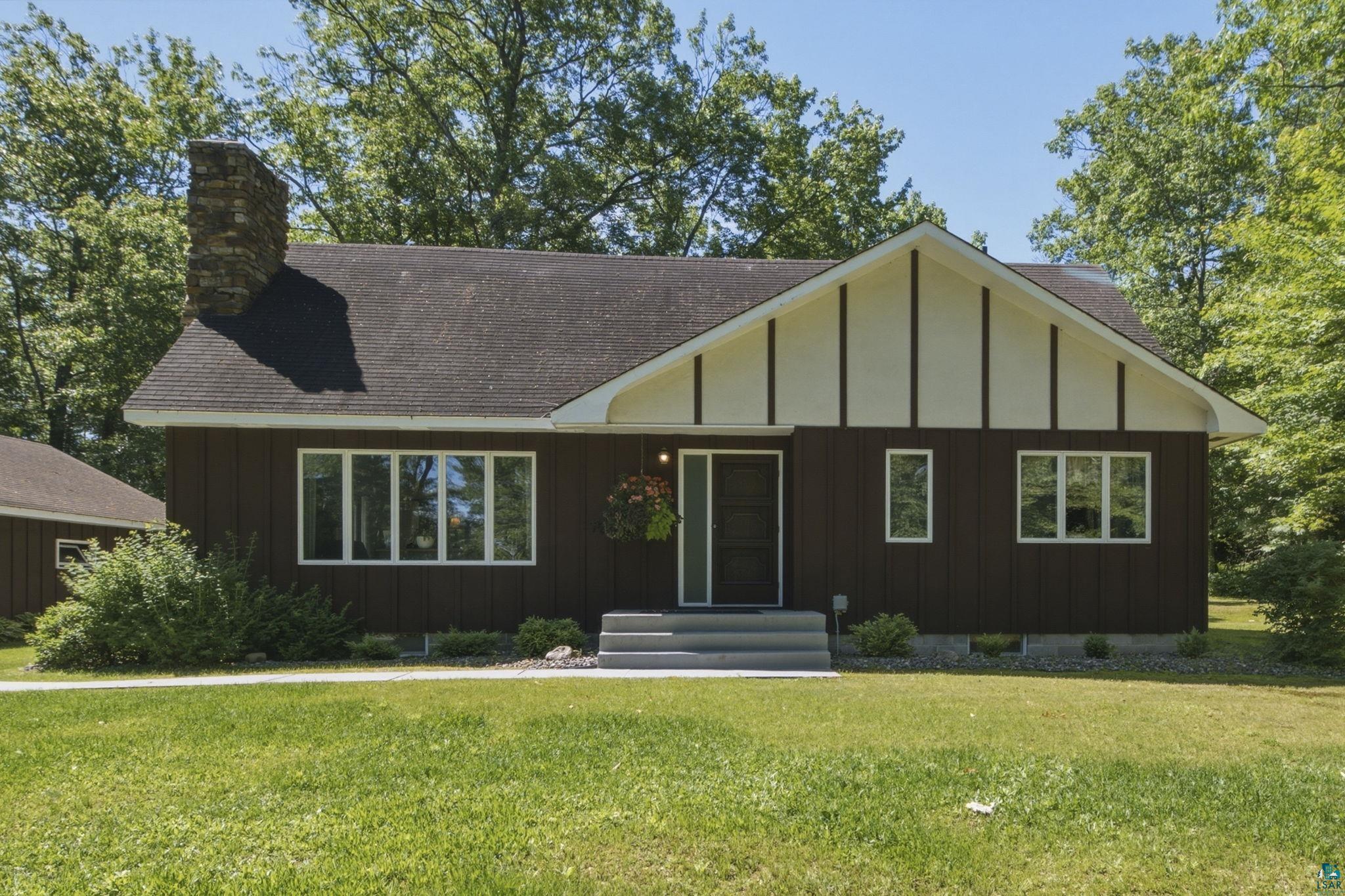 27485 South Kane Road Ashland, WI 54806 - Photo 27 of 35 Brown siding exterior with a contrasting light-colored gable, a prominent stone chimney, and multiple windows
