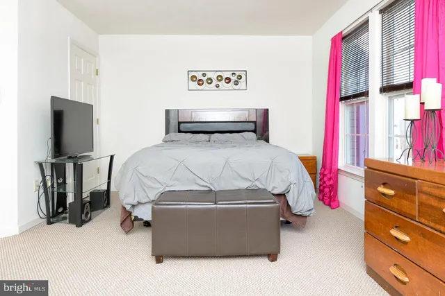 a bedroom with a bed and a flat tv screen on dresser