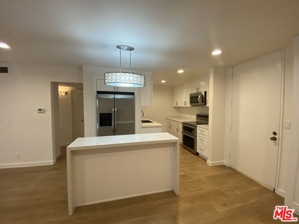 1101 Raintree Circle, Unit 101 Culver City, CA 90230 - Photo 7 of 12 a view of a kitchen with kitchen island a sink stainless steel appliances and cabinets