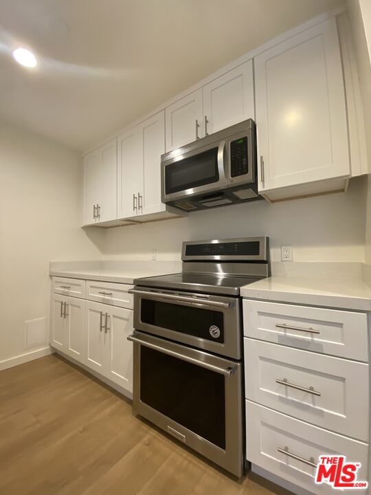 1101 Raintree Circle, Unit 101 Culver City, CA 90230 - Photo 8 of 12 a kitchen with stainless steel appliances granite countertop a stove and a microwave