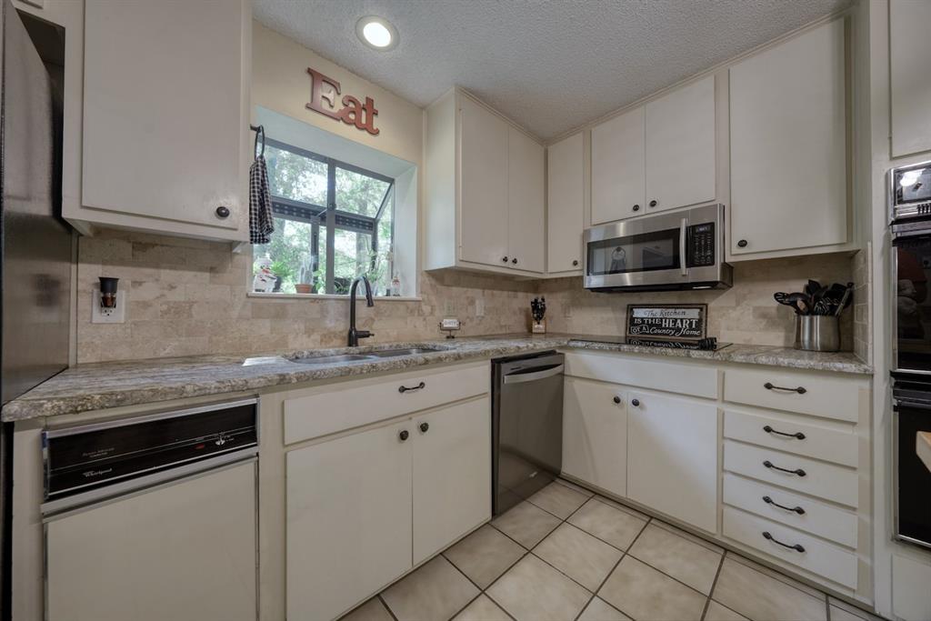 1649 Morningside Trail Hideaway, TX 75771 - Photo 11 of 40 a kitchen with granite countertop white cabinets stainless steel appliances a sink and a window