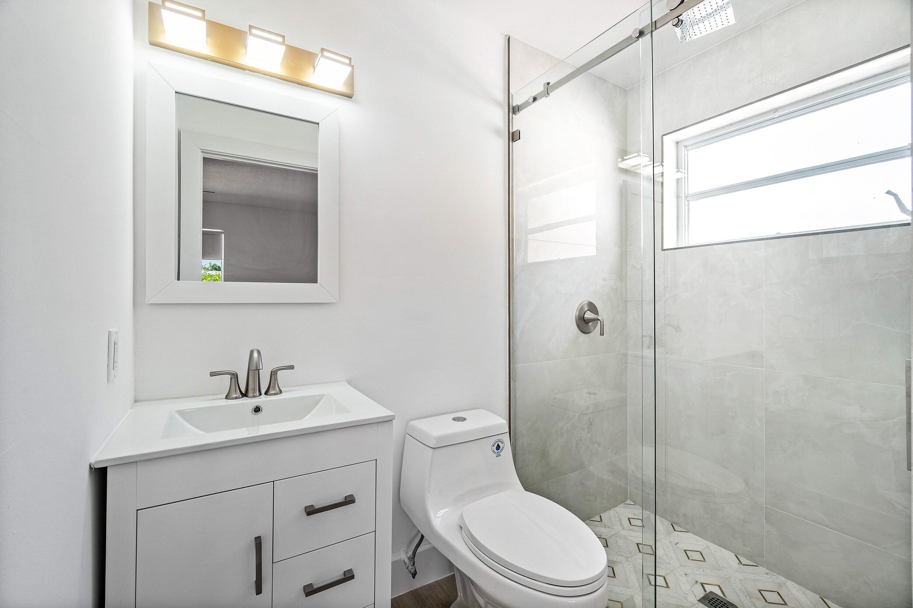 1531 Northwest 4th Street Boca Raton, FL 33486 - Photo 27 of 34 a bathroom with a sink a mirror a toilet and shower
