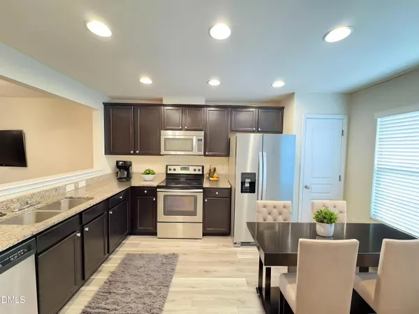 a large kitchen with stainless steel appliances kitchen island granite countertop a stove top oven a sink dishwasher a dining table and chairs