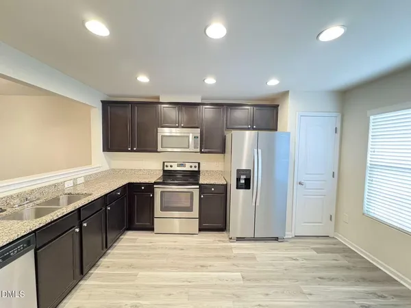 a large kitchen with stainless steel appliances granite countertop a stove a sink and a refrigerator