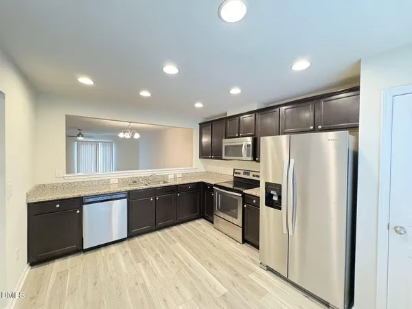 a large kitchen with stainless steel appliances granite countertop a refrigerator and a sink