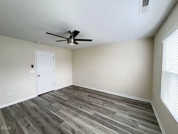 a view of empty room with wooden floor and fan