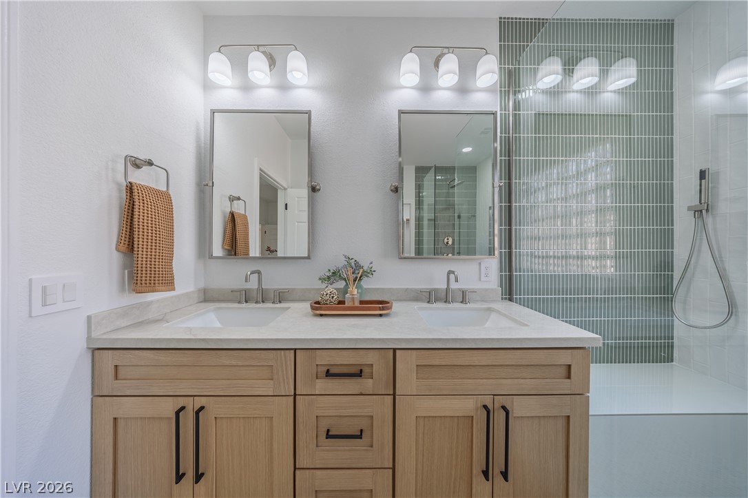 10982 Village Ridge Lane Las Vegas, NV 89135 - Photo 10 of 12 Dual vanities with stone counters and a modern tiled shower define this well-appointed primary bathroom.