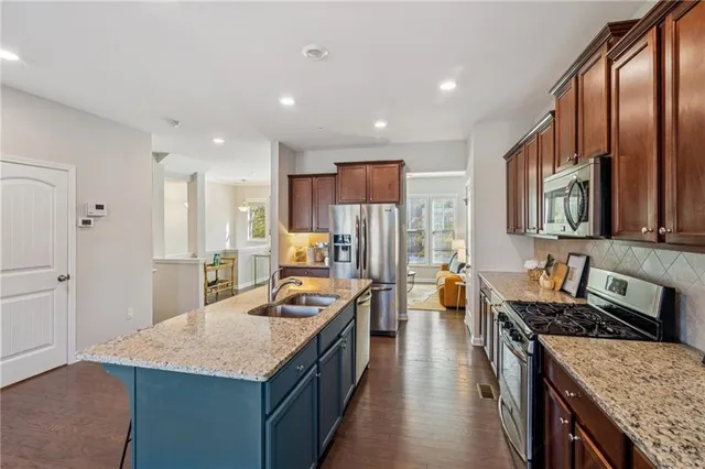 a kitchen with stainless steel appliances granite countertop a stove a refrigerator a sink dishwasher with wooden cabinets and floor