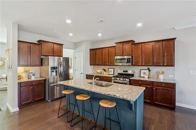 a kitchen with stainless steel appliances granite countertop a table chairs sink refrigerator and cabinets