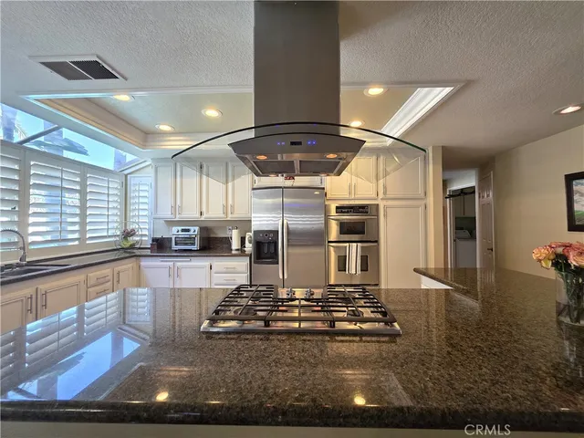 a living room with stainless steel appliances kitchen island granite countertop a stove and a sink