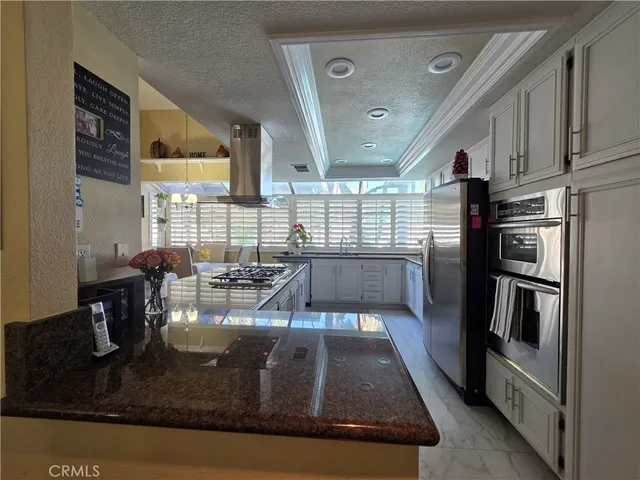 a living room with stainless steel appliances kitchen island granite countertop a refrigerator a stove a sink dishwasher and cabinets