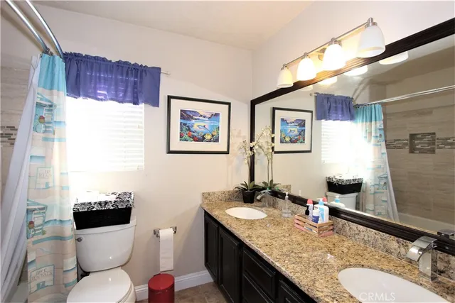 a bathroom with a granite countertop double vanity sink and a mirror
