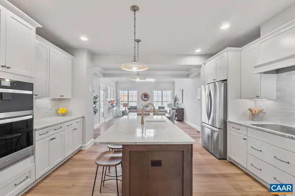 a kitchen with stainless steel appliances kitchen island granite countertop a refrigerator a sink dishwasher a stove and white cabinets with wooden floor