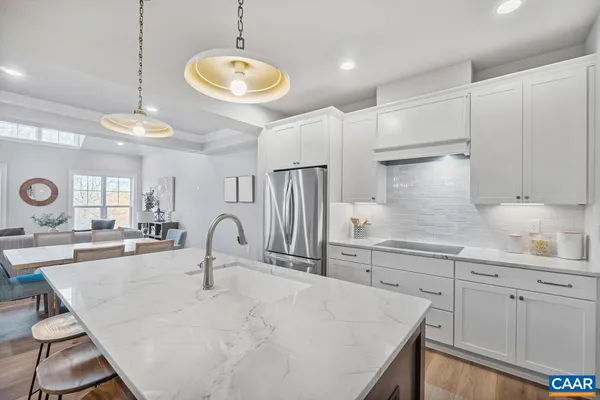 a kitchen with kitchen island granite countertop a stove a sink a refrigerator and white cabinets with wooden floor