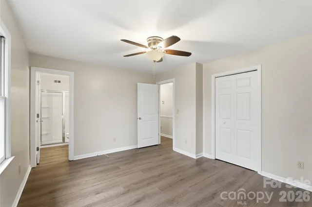 an empty room with wooden floor ceiling fan and window